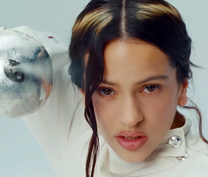 Rosalía en traje de esgrima blanco, protegida contra el desamor, con perros blanco y negro simbolizando caos emocional interno.