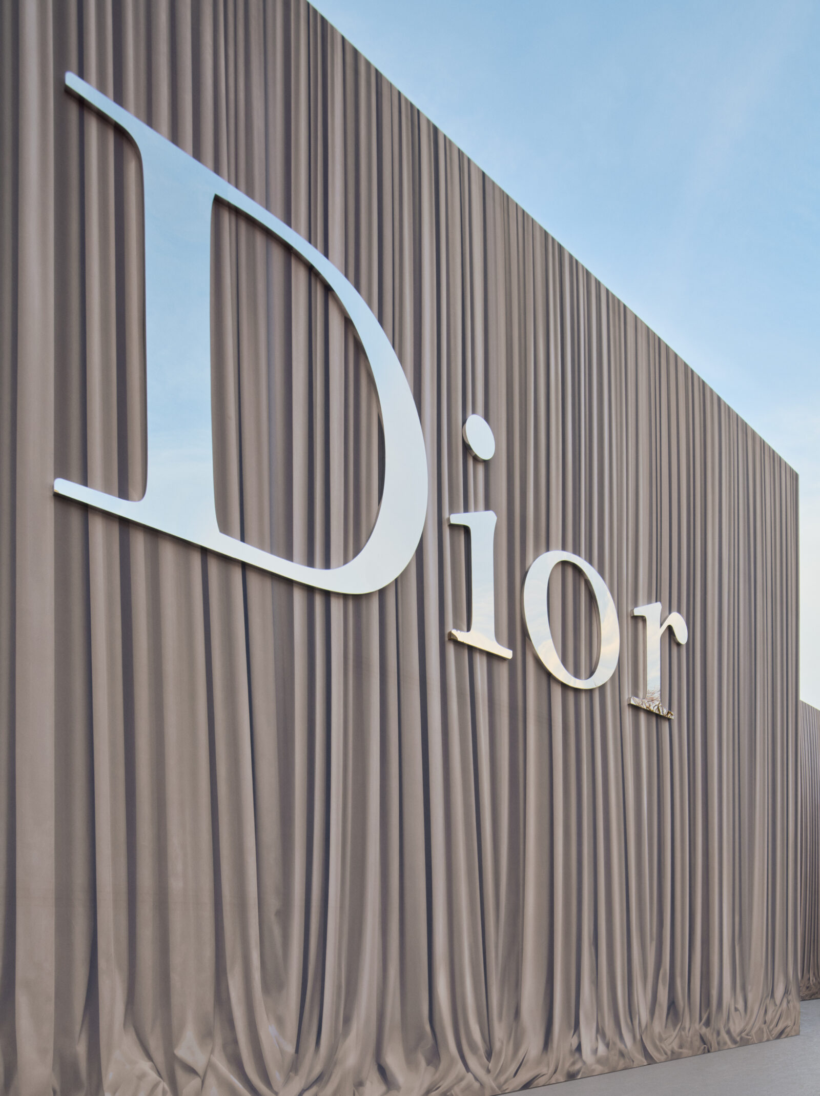 Logo Dior icónico bordado en tweed marrón Donegal, evocando los códigos de sastrería que Jonathan Anderson subvierte para Invierno 2026-2027.