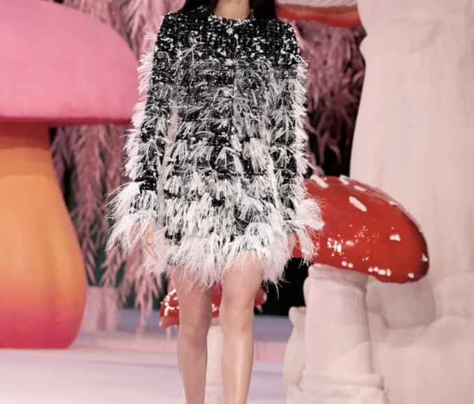 Vestidos de tul alado cascatean desde corsets raso etéreos, mientras tweed esporulado moldea chaquetas vivas con solapas troncos retorcidos.