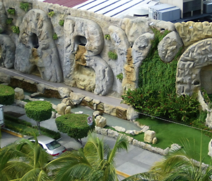 Vista nocturna icónica del Baby ‘O en Acapulco: fachada iluminada con luces neón rosas y blancas sobre la Costera Miguel Alemán.