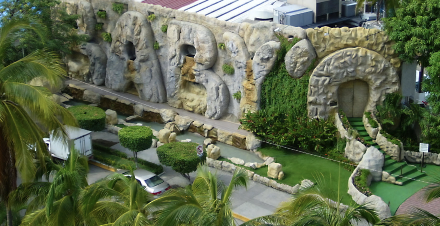 Vista nocturna icónica del Baby ‘O en Acapulco: fachada iluminada con luces neón rosas y blancas sobre la Costera Miguel Alemán.