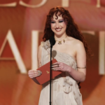 Escena vibrante de la gala de los Grammy 2026: artistas en el escenario principal con trofeos dorados y luces brillantes, celebrando logros musicales.