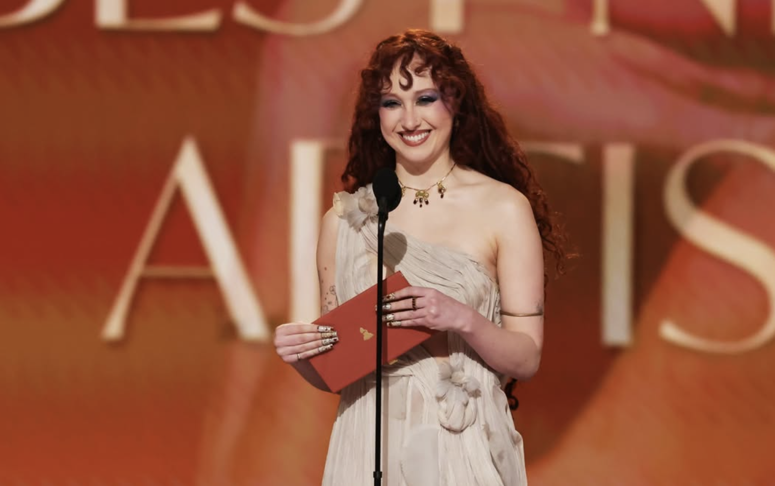 Escena vibrante de la gala de los Grammy 2026: artistas en el escenario principal con trofeos dorados y luces brillantes, celebrando logros musicales.