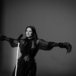 Laura Pausini en el videoclip de “Mariposa Tecknicolor”, rodeada de mariposas vibrantes tecknicolor en un escenario romano dinámico, simbolizando transformación y libertad. ​