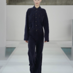 Desfile COS Primavera-Verano 2026 en Seúl: modelos emergen en neblina brutalista con looks en grises y el Monument Tote icónico.