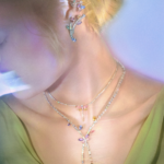 Ariana Grande x Swarovski: Vista cercana de libélula de cristal arcoíris y flores iridiscentes de la segunda colección cápsula, inspirada en jardines fantásticos y auroras boreales. Joyería mágica de lujo.