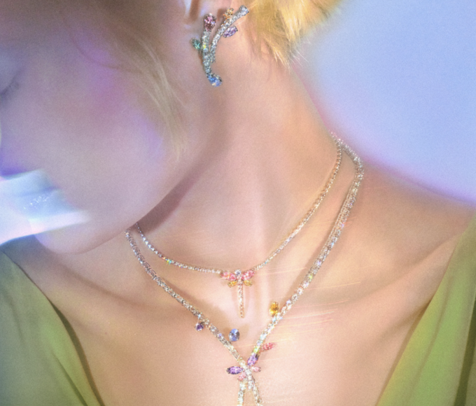 Ariana Grande x Swarovski: Vista cercana de libélula de cristal arcoíris y flores iridiscentes de la segunda colección cápsula, inspirada en jardines fantásticos y auroras boreales. Joyería mágica de lujo.