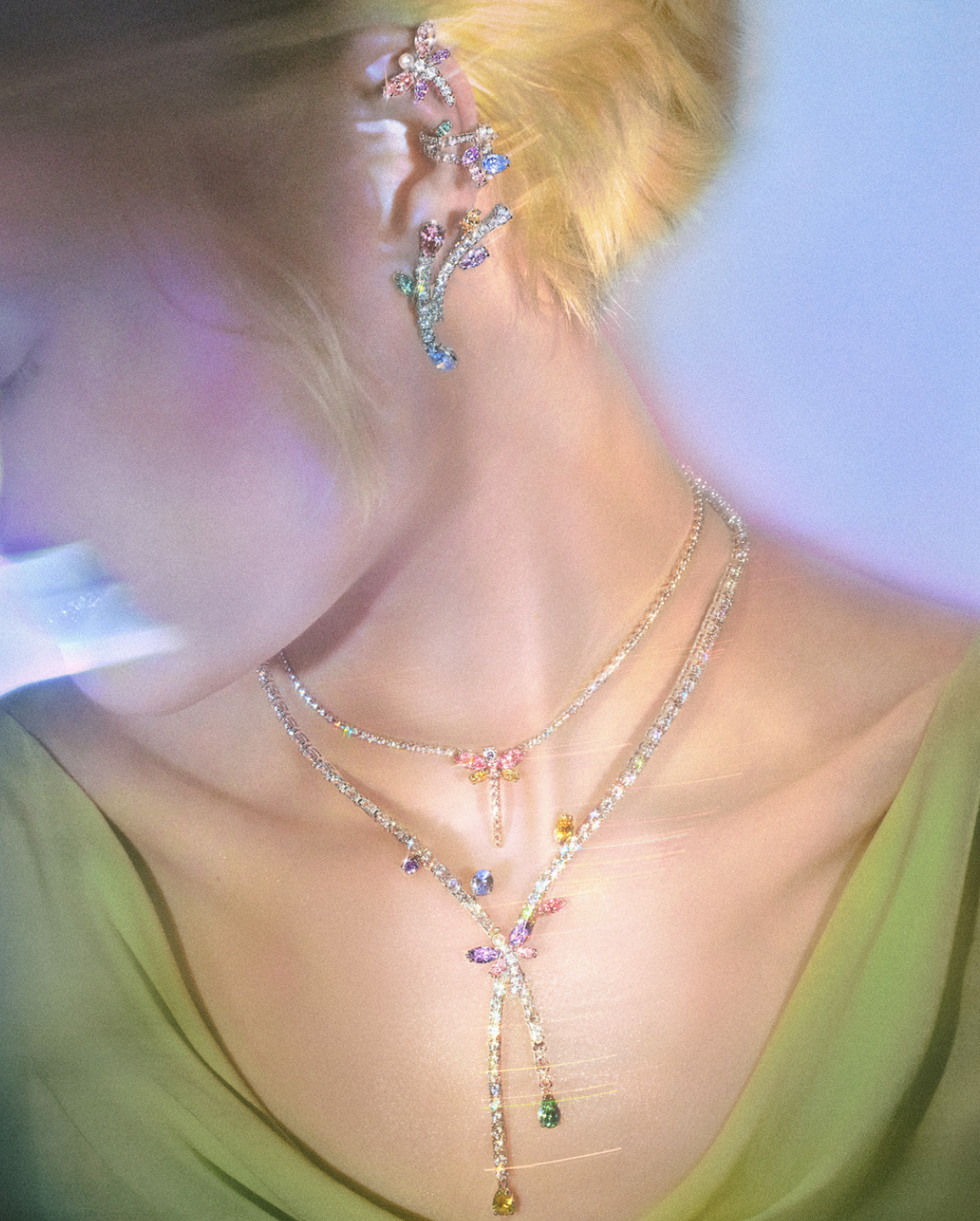 Ariana Grande x Swarovski: Vista cercana de libélula de cristal arcoíris y flores iridiscentes de la segunda colección cápsula, inspirada en jardines fantásticos y auroras boreales. Joyería mágica de lujo.