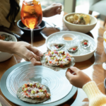 Mesa elegante decorada con flores y platillos gourmet en Sofitel Mexico City Reforma durante una celebración especial por el Día de las Madres con vista a la ciudad.
