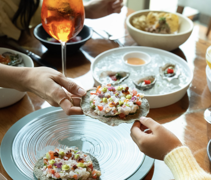 Mesa elegante decorada con flores y platillos gourmet en Sofitel Mexico City Reforma durante una celebración especial por el Día de las Madres con vista a la ciudad.