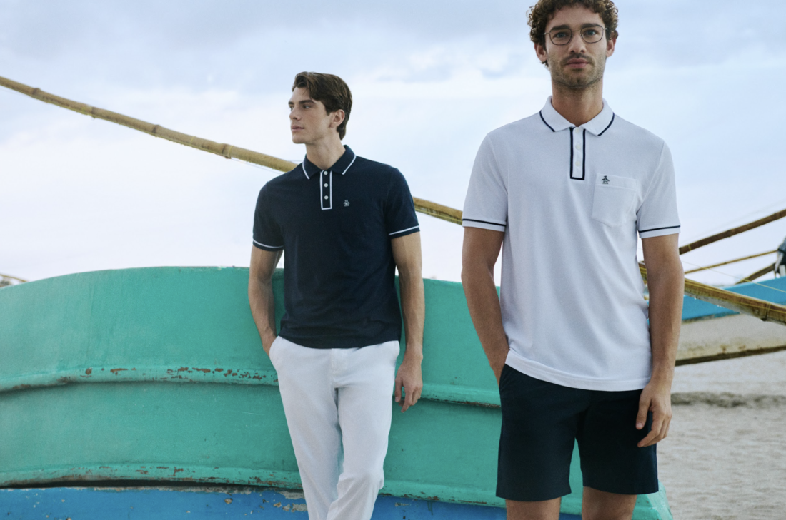 Hombre con look casual de Original Penguin combinando polo y prendas ligeras en un entorno que fusiona lo natural con lo urbano, reflejando un estilo relajado y auténtico.