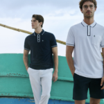 Hombre con look casual de Original Penguin combinando polo y prendas ligeras en un entorno que fusiona lo natural con lo urbano, reflejando un estilo relajado y auténtico.