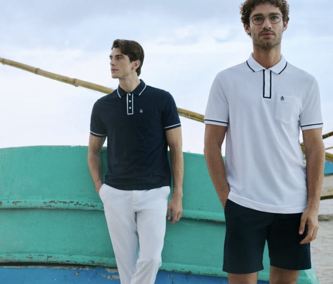 Hombre con look casual de Original Penguin combinando polo y prendas ligeras en un entorno que fusiona lo natural con lo urbano, reflejando un estilo relajado y auténtico.