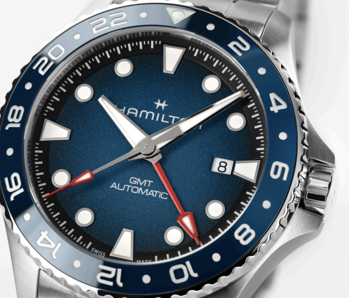 Relojes Hamilton Khaki Navy Scuba Auto 40 mm y Scuba Auto GMT en acero inoxidable, con esfera azul y bisel giratorio, presentados sobre un fondo de inspiración marina.