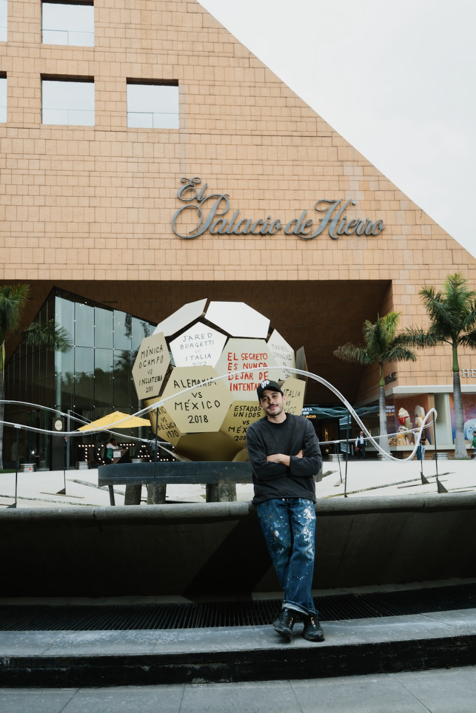 Román de Castro posa junto a su intervención artística para La Fiesta Está en El Palacio, una obra monumental inspirada en un balón de fútbol que reflexiona sobre la perseverancia y la memoria colectiva.