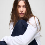 Hailey Bieber posa con prendas de la colección The Hailey Jean para Gap, luciendo jeans de inspiración noventera y una camiseta blanca en la campaña de edición limitada.