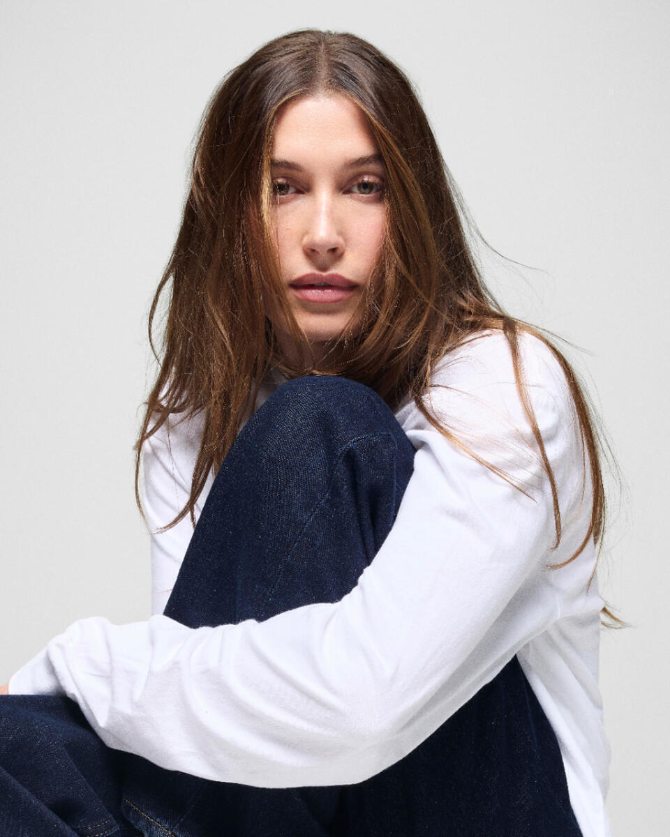 Hailey Bieber posa con prendas de la colección The Hailey Jean para Gap, luciendo jeans de inspiración noventera y una camiseta blanca en la campaña de edición limitada.