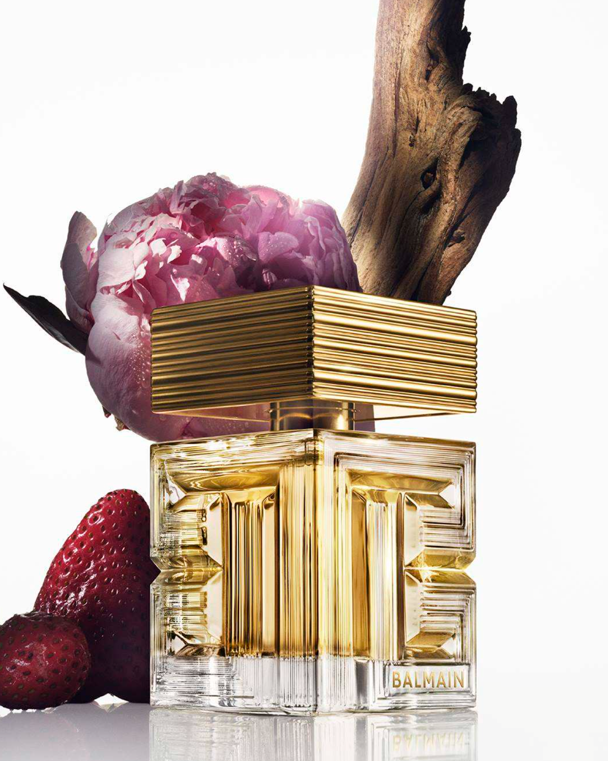 Frasco de Destin de Balmain, una fragancia floral-frutal de lujo, presentado en un diseño cúbico de vidrio transparente con detalles dorados y el icónico motivo de laberinto de Balmain.